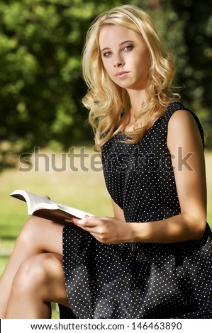 beautiful blonde girl writing a book in green garden