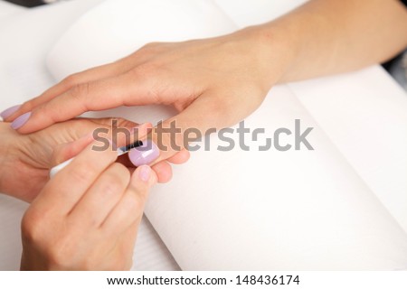 Manicure - Beautiful manicured woman's nails with violet nail polish on soft white towel.