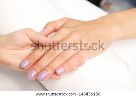 Manicure - Beautiful manicured woman's nails with violet nail polish on soft white towel.