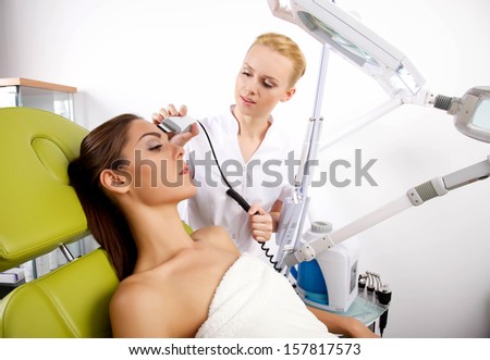 Young brunette woman receiving laser therapy. Spa studio shot