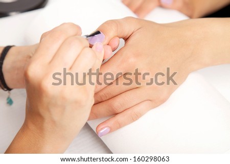 Manicure - Beautiful manicured woman\'s nails with violet nail polish on soft white towel.