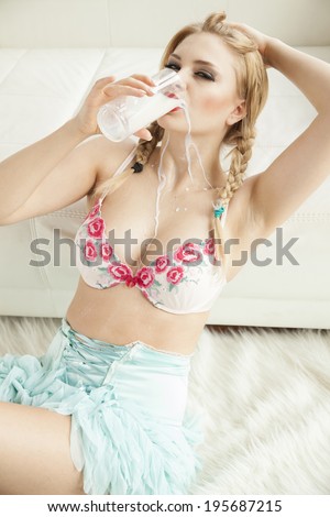 Young adult sensuality blonde girl in white lingerie drinking milk