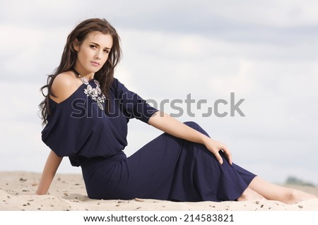 Young adult attractive sexy and sensuality brunette woman posing in violet dress on the sand