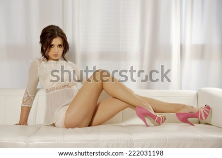 Beautiful attractive and sexy young adult sensuality brunette pretty woman on the white sofa in luxury style apartment