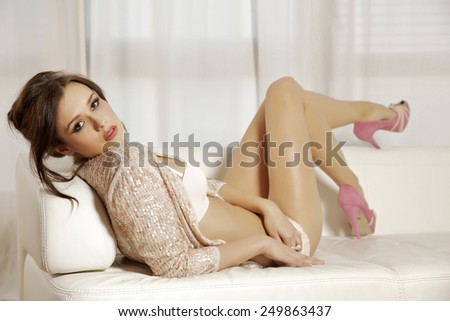 Beautiful sexy young adult attractive and sensuality pretty brunette woman on the white sofa in luxury style hotel apartment