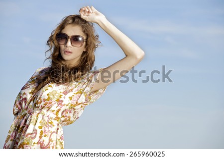 portrait of a beautiful attractive and sensuality young adult pretty brunette woman in sunglasses on background blue sunlight sky