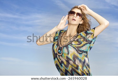 portrait of a beautiful attractive and sensuality young adult pretty brunette woman in sunglasses on background blue sunlight sky