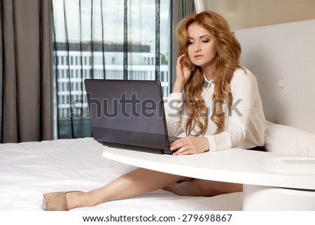 Young adult beauty attractive sexy and sensuality happy pretty blonde businesswoman using laptop while lying on bed in hotel room