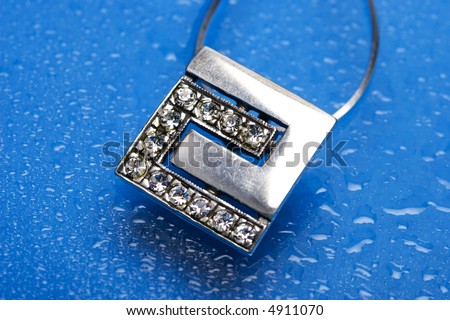beautiful silver necklace with diamonds on blue background with water drops