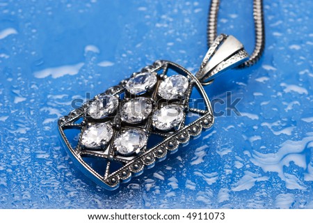 beautiful silver necklace with diamonds on blue background with water drops