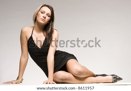 beautiful blond model lying on grey background wearing black mini dress