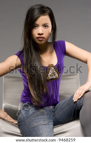 studio shot of beautiful Asian model wearing purple blouse and jeans