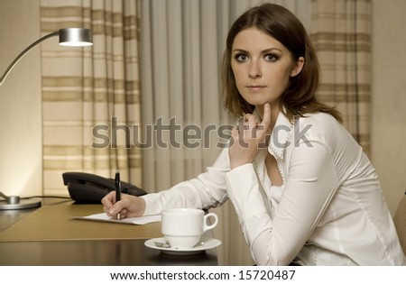 beautiful young businesswoman sitting at the desk and writing