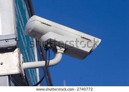 White surveillance camera mounted on the outside of a building
