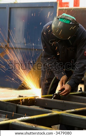 Steel worker using an acetylene torch to cut steel tubing