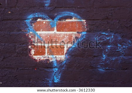Paint that has peeled to reveal the brick with a blue spray painted tag in the shape of a heart