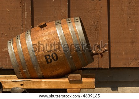 Old oak whiskey barrel on the side of a wooden building.