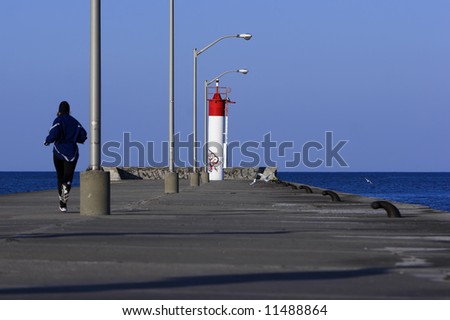 Runner jogging to the end of a concrete pier.