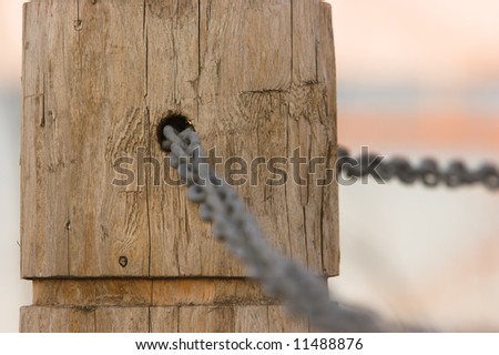 Chain link through a hole in a post. Narrow depth of focus.