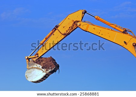 Excavator scoop full of dirt at a construction site.