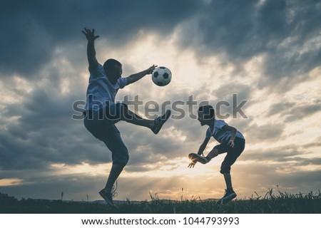 Father and young little boy playing in the field  with soccer ball. Concept of sport.