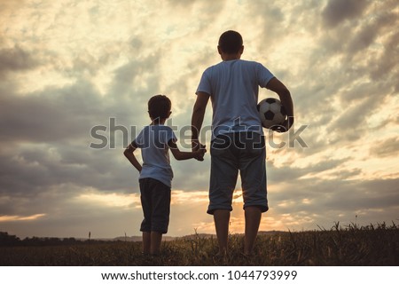 Father and young little boy playing in the field  with soccer ball. Concept of sport.