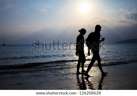 Silhouette of couple taking a walk on beach in sunset