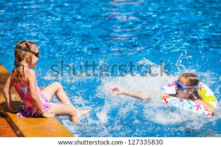 two happy little girls splashing around in the pool