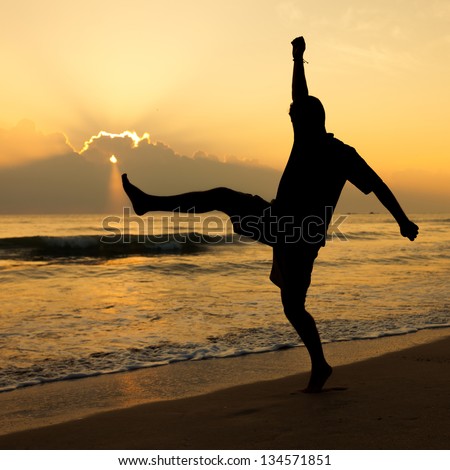Happy man jumping over sea. Sand beach at dawn.