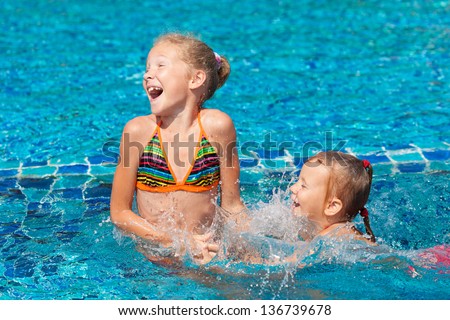 two happy little girls playing around in the pool