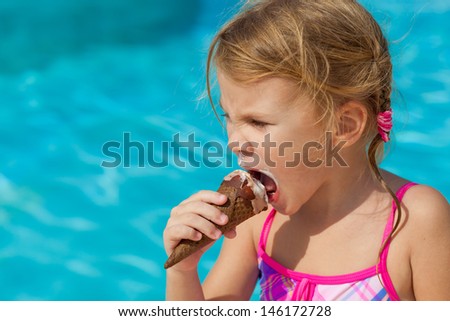 little girl eating ice cream near the pool