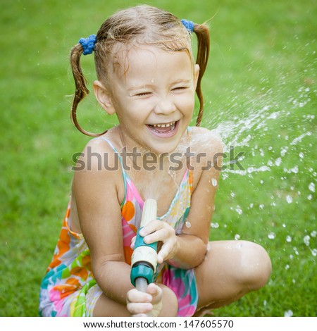 Happy girl pours water from a hose