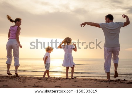 Happy beautiful family dancing at the  beach on the  dawn time.