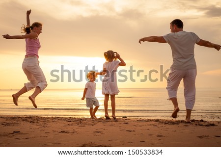 Happy beautiful family dancing at the  beach on the  dawn time.
