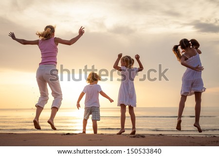 Happy beautiful family dancing on the  beach on the  dawn time.