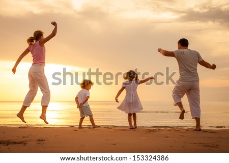 Happy Beautiful Family Dancing On The Beach On The Dawn Time.