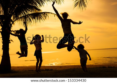 Happy beautiful family dancing on the  beach on the  dawn time.