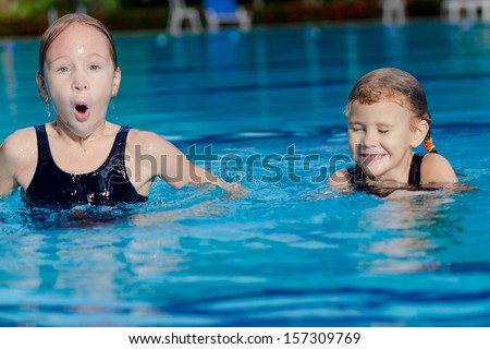 two happy little girls playing around in the pool