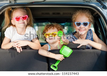 two little girls  and boy sitting in the car