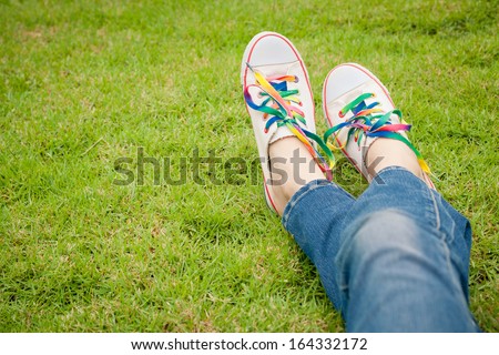 white sneakers on girl legs on grass during sunny serene summer day.