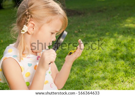 one little girl with magnifying glass outdoors in the day time