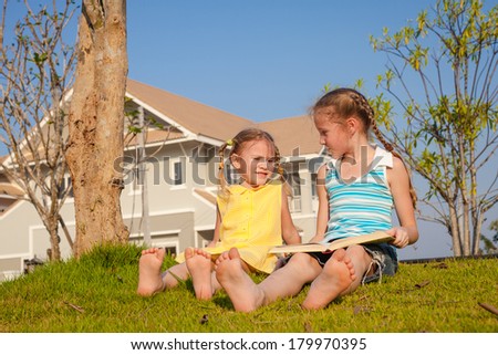two little girls sitting and reading a book on nature