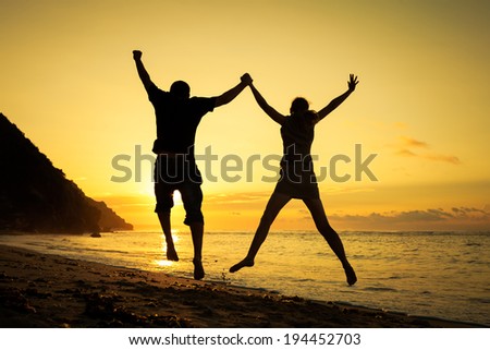 Happy family jumping on the beach at the dawn time