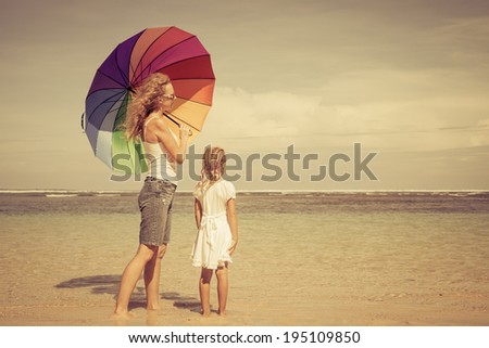 mother and  daughter walking on the beach at the day time