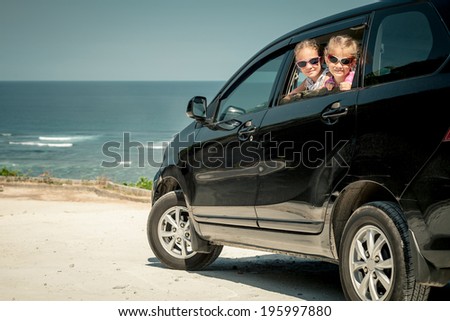 two sisters sitting in a car on the beach