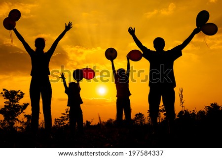 Happy  family  with balloons  standing on the road at the  sunset time. Evening party on the nature