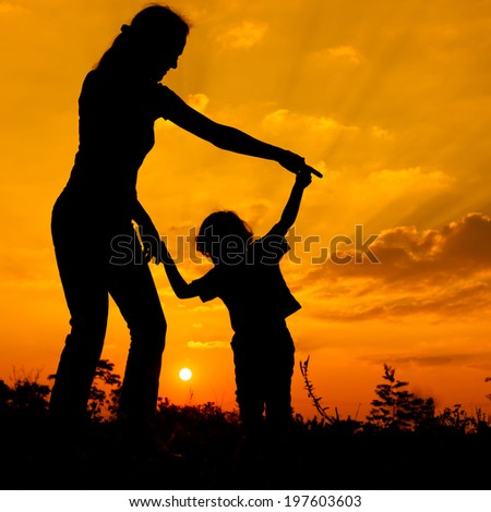 silhouette of a mother and son who play outdoors at sunset background