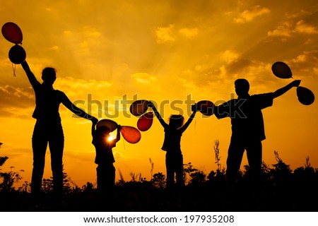 Happy  family  with balloons  standing on the road at the  sunset time. Evening party on the nature