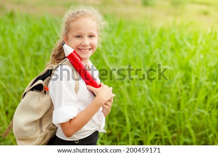 happy schoolgirl standing near the house at the day time and ready to go to school