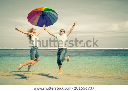 happy couple jumping on the beach at the day time